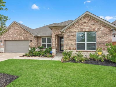 This is a single-story brick home featuring a well-maintained lawn, a two-car garage, and a welcoming entrance with a modest garden. | Image 2