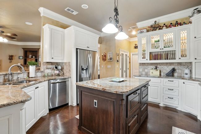 Kitchen with backsplash, ornamental molding, white cabinets, and appliances with stainless steel finishes | Image 12
