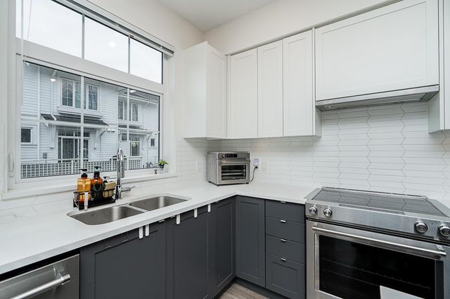 Kitchen featuring white cabinets, appliances with stainless steel finishes, gray cabinets, light countertops, and a sink | Image 13