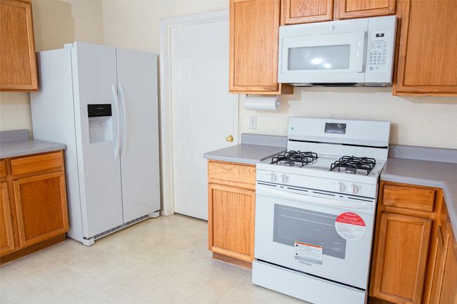 Kitchen with white appliances, light countertops, and brown cabinetry | Image 10