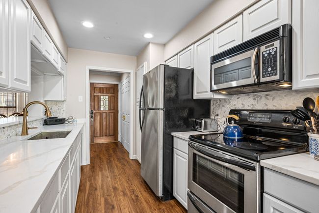 Kitchen with stainless steel appliances, white cabinetry, decorative backsplash, recessed lighting, and dark wood-type flooring | Image 6