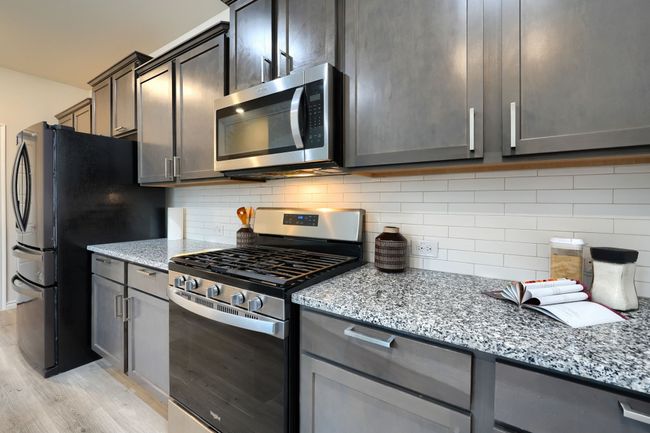 Kitchen with appliances with stainless steel finishes, light wood-style flooring, light stone countertops, and decorative backsplash | Image 11
