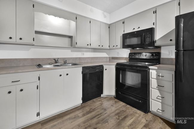 Kitchen featuring black appliances, wood finished floors, and light countertops | Image 13