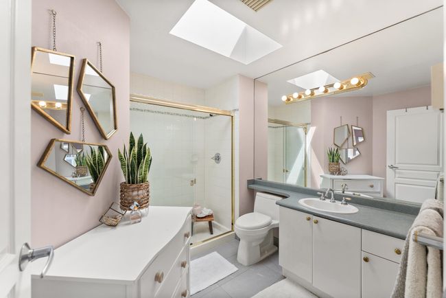 Bathroom featuring a skylight, toilet, a stall shower, vanity, and tile patterned flooring | Image 28