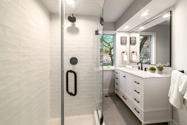 The secondary, full-size bathroom maximizes space with an all-glass stall shower and porcelain tilework. | Image 23