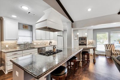 Kitchen featuring white cabinetry, a large island, and sink | Image 3