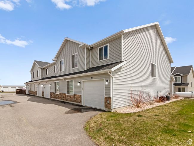 View of home's exterior featuring central air condition unit, a yard, an attached garage, and aphalt driveway | Image 8