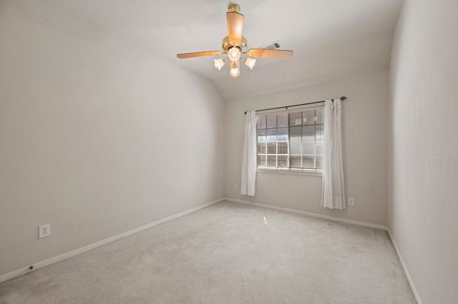 Unfurnished room featuring lofted ceiling, light colored carpet, baseboards, visible vents, and a ceiling fan | Image 28