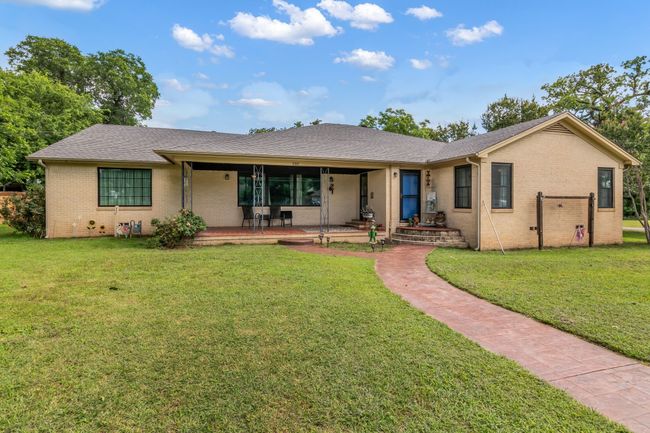 Ranch-style home featuring brick siding, a front yard, covered porch, and a shingled roof | Image 32