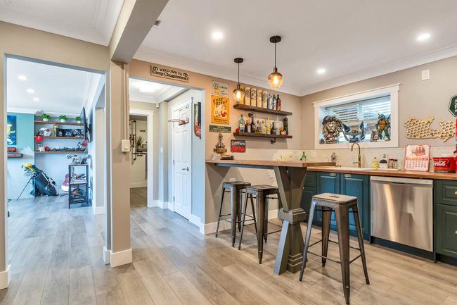 Bar featuring light wood finished floors, a sink, crown molding, wet bar, and stainless steel dishwasher | Image 28