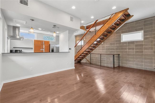 Unfurnished living room featuring wood finished floors, recessed lighting, stairs, and tile walls | Image 10