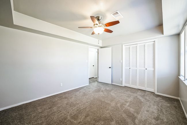 Unfurnished bedroom with visible vents, a raised ceiling, carpet, and baseboards | Image 17