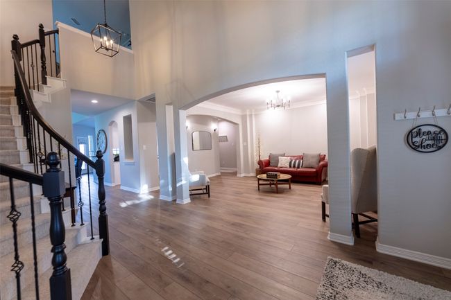 Entrance foyer with a chandelier, arched walkways, wood finished floors, stairway, and a towering ceiling | Image 6