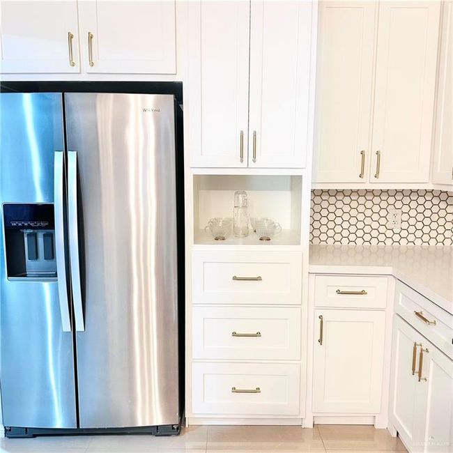 Kitchen featuring stainless steel fridge, light countertops, and white cabinetry | Image 8