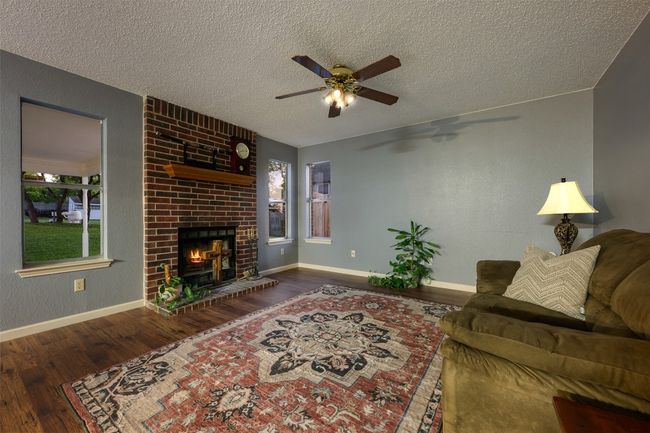 Living area with a textured ceiling, wood finished floors, baseboards, and a ceiling fan | Image 14