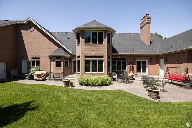 Back of house featuring a chimney, brick siding, a yard, and a patio | Image 81