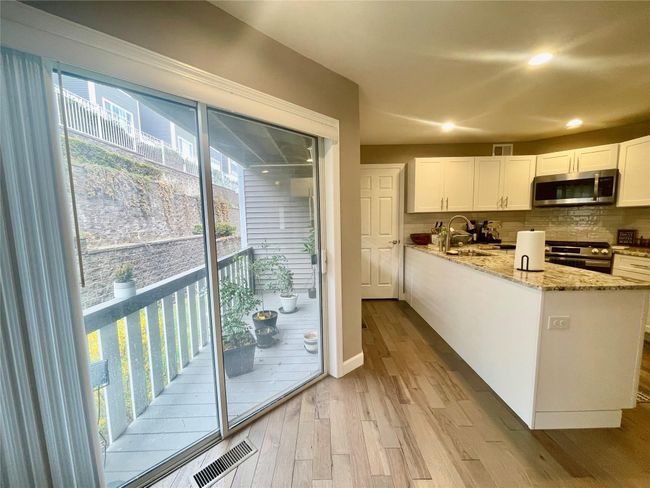 Kitchen featuring light wood-style flooring, a sink, visible vents, white cabinetry, and appliances with stainless steel finishes | Image 12