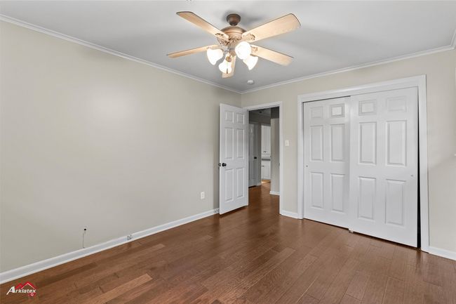 Unfurnished bedroom with wood finished floors, baseboards, crown molding, a closet, and a ceiling fan | Image 14