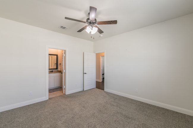 Unfurnished bedroom featuring visible vents, ensuite bathroom, a ceiling fan, carpet, and baseboards | Image 19