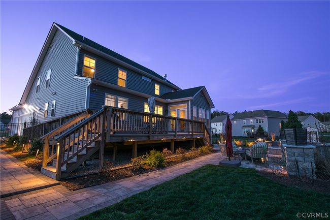 Back house at dusk with a wooden deck, a patio, and a yard | Image 46