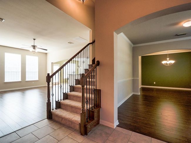 Stairs featuring arched walkways, a chandelier, wood finished floors, ornamental molding, and a ceiling fan | Image 5
