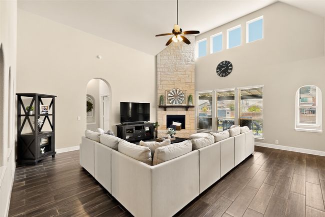 Living area with high vaulted ceiling, a ceiling fan, arched walkways, dark wood-style flooring, and baseboards | Image 6