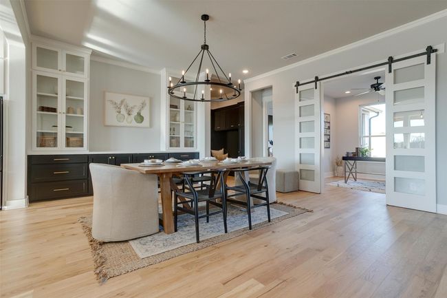 Dining space featuring a barn door, crown molding, light hardwood / wood-style floors, and ceiling fan with notable chandelier | Image 9