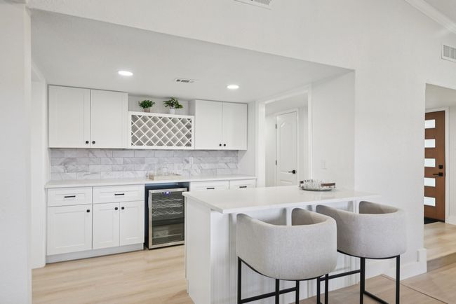 Indoor dry bar featuring beverage cooler, light wood-style flooring, tasteful backsplash, and recessed lighting | Image 19