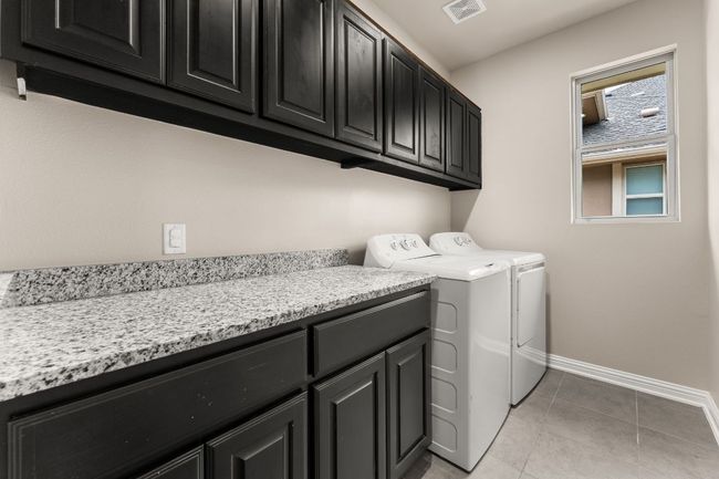 Washroom with cabinet space, washer and dryer, and light tile patterned flooring | Image 23