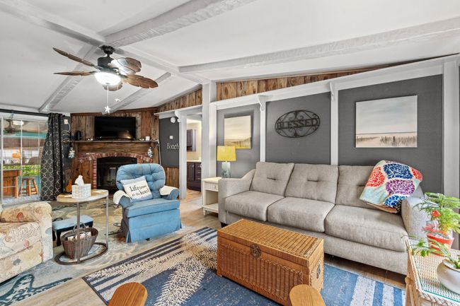 Living room featuring hardwood / wood-style floors, vaulted ceiling with beams, ceiling fan, and a brick fireplace | Image 8