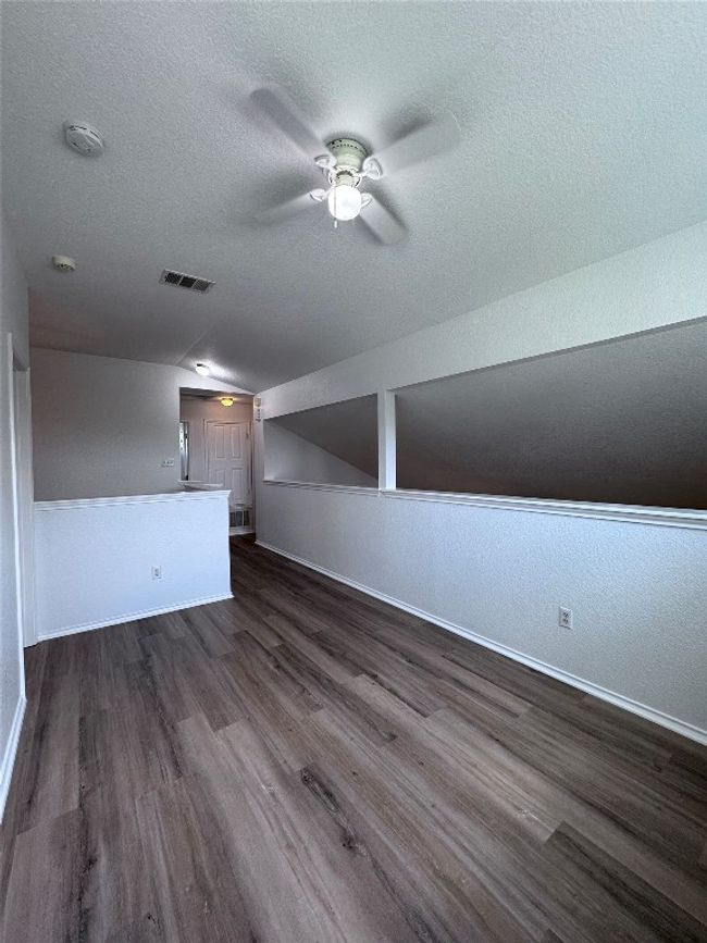 Additional living space featuring ceiling fan, dark wood-style flooring, vaulted ceiling, and a textured ceiling | Image 23