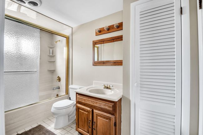 Full bathroom featuring tile patterned flooring, toilet, vanity, and enclosed tub / shower combo | Image 20