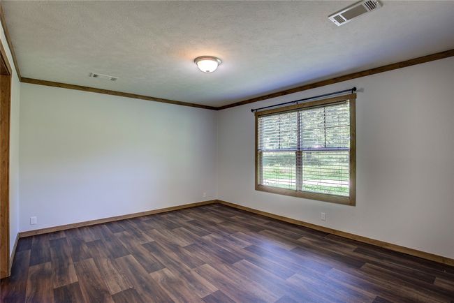 Empty room with dark wood-style flooring, crown molding, and a textured ceiling | Image 11