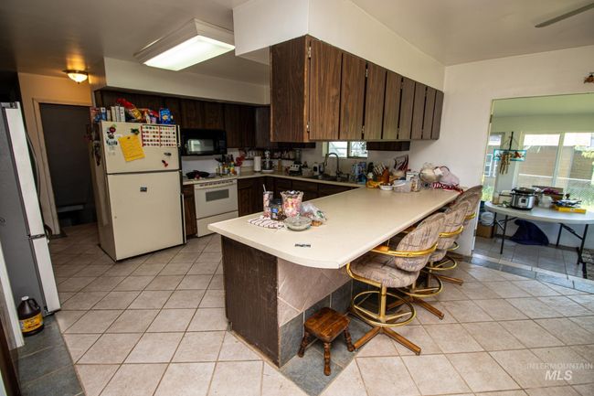 Kitchen with white appliances, a peninsula, light countertops, and light tile patterned floors | Image 18