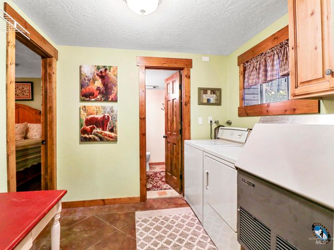 Laundry room featuring cabinet space, separate washer and dryer, a textured ceiling, and light tile patterned floors | Image 33