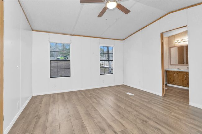 Empty room featuring lofted ceiling, wood finished floors, a ceiling fan, and ornamental molding | Image 13