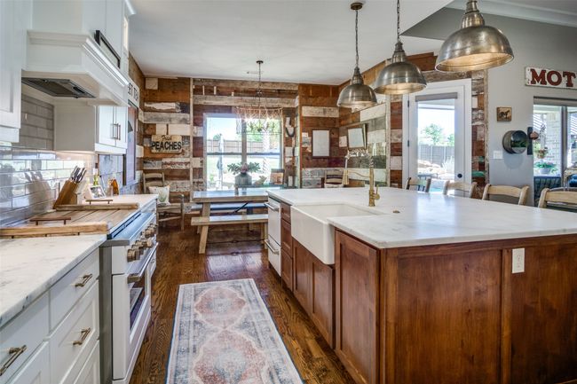 Kitchen with a sink, high end stove, tasteful backsplash, dark wood finished floors, and hanging light fixtures | Image 13