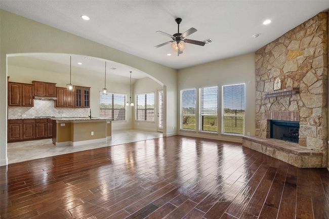 Unfurnished living room featuring light wood-style floors, a fireplace, ceiling fan, and recessed lighting | Image 14