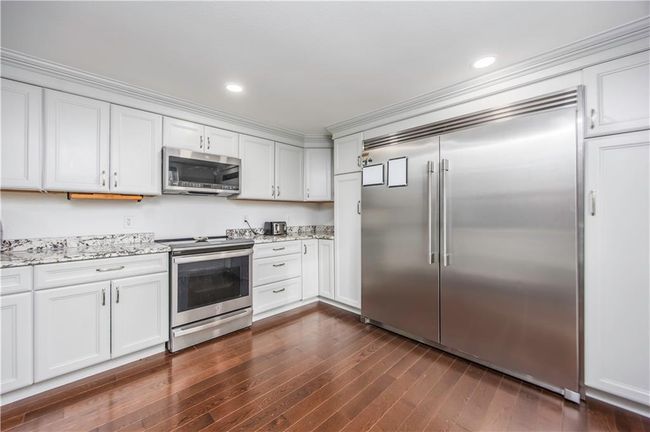 Kitchen with recessed lighting, light stone countertops, appliances with stainless steel finishes, and dark wood finished floors | Image 34