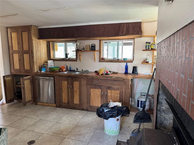 Kitchen featuring open shelves, dishwasher, a brick fireplace, and a sink | Image 14