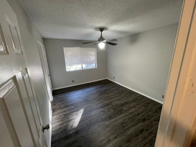 Unfurnished bedroom with dark wood-type flooring, a textured ceiling, and ceiling fan | Image 8