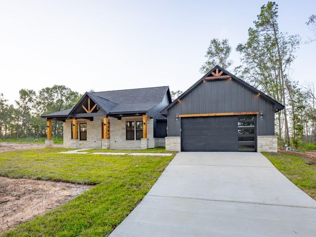 A spacious concrete driveway leads to the modern black-paneled garage door with glass inserts—both functional and stylish for today’s lifestyle. | Image 37