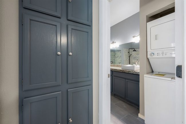 Full bath featuring a tile shower, stacked washer / dryer. | Image 14