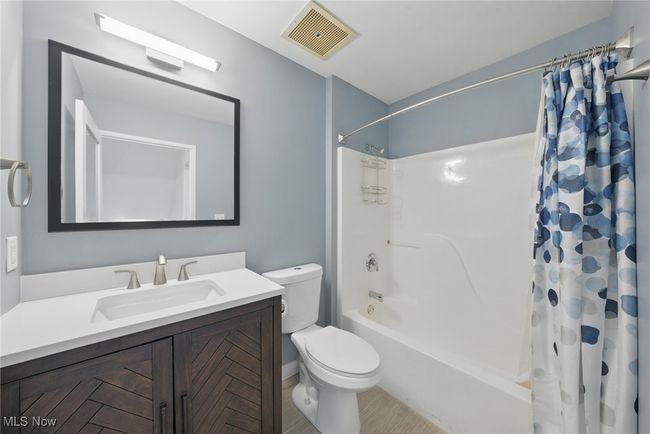 Full bath featuring tile patterned flooring, visible vents, toilet, vanity, and shower / tub combo with curtain | Image 27