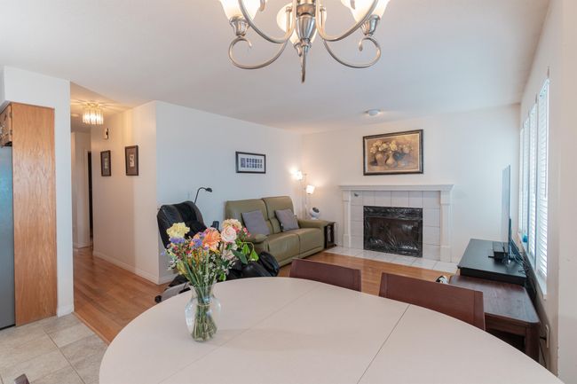 Dining area featuring a chandelier, a fireplace, light wood-style floors, and baseboards | Image 13