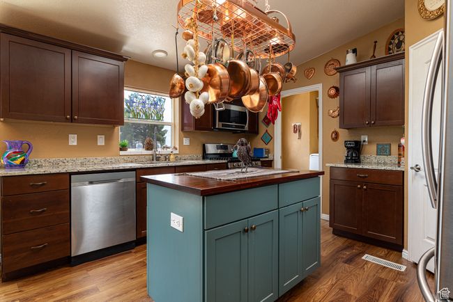 Kitchen with decorative light fixtures, sink, a center island, stainless steel appliances, and light wood-type flooring | Image 7