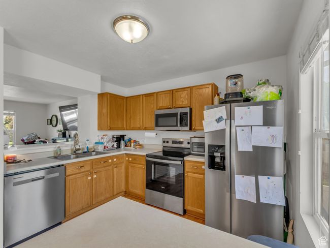 Kitchen featuring stainless steel appliances, a sink, and light countertops | Image 11
