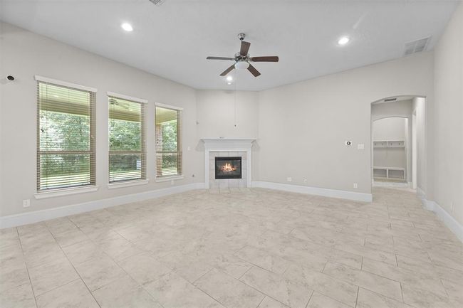 Picture yourself relaxing in this bright, open living room—huge windows flood the space with light and frame serene woods outside. The cool tile floor and cozy fireplace make it perfect for everything from morning coffee to movie nights with friends. | Image 7