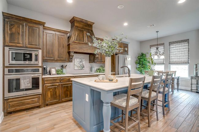 Kitchen with stainless steel appliances, light countertops, an island with sink, recessed lighting, and backsplash | Image 12
