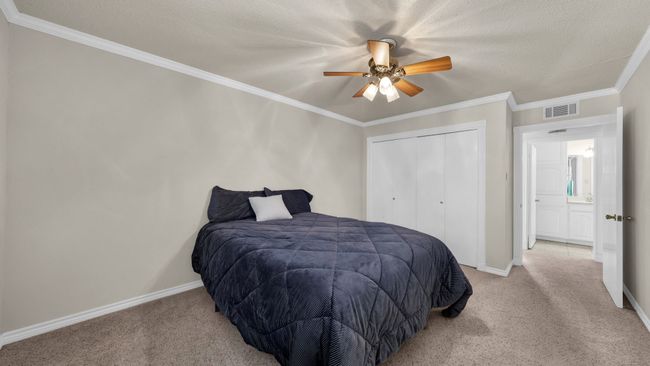 Carpeted bedroom with ceiling fan, ornamental molding, a closet, and a textured ceiling | Image 21